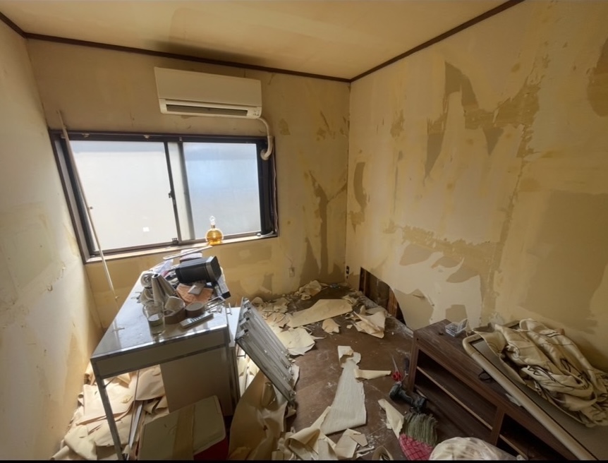 施工前の部屋。壁紙が剥がれ、床や家具が散乱している状態